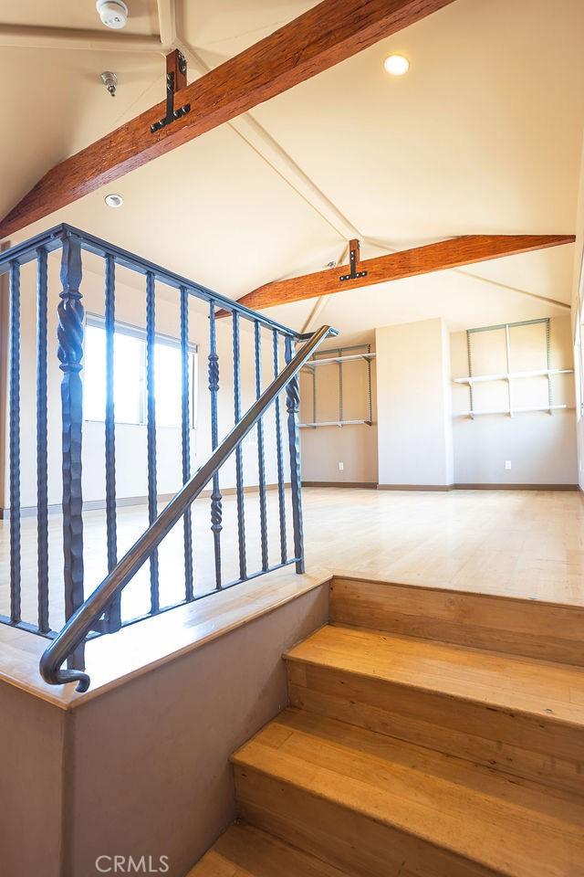 stairway featuring wood-type flooring and vaulted ceiling with beams