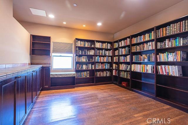 unfurnished room with recessed lighting, light wood finished floors, and wall of books