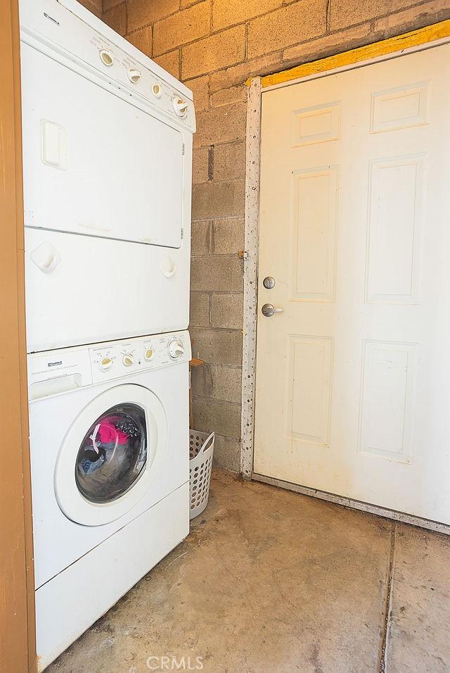 clothes washing area featuring stacked washing maching and dryer and laundry area