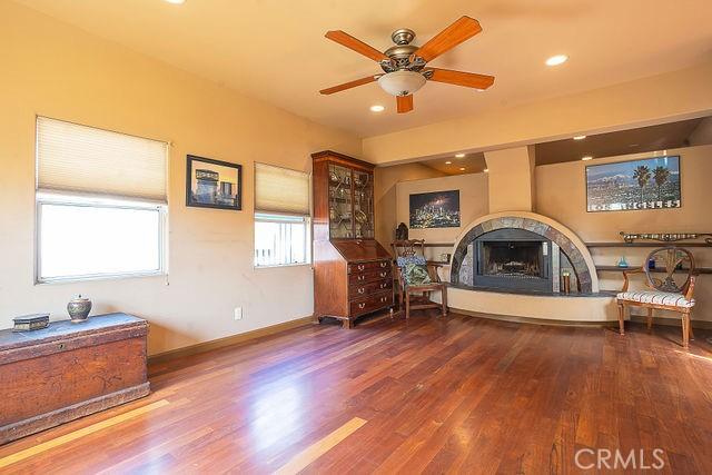sitting room featuring ceiling fan, wood finished floors, a fireplace with raised hearth, and recessed lighting