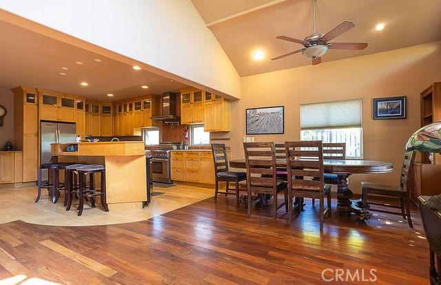 dining room with a ceiling fan, light wood finished floors, and high vaulted ceiling