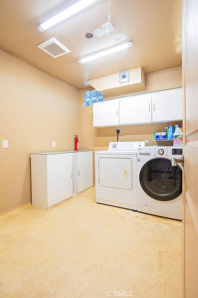 clothes washing area with cabinet space and washer and dryer