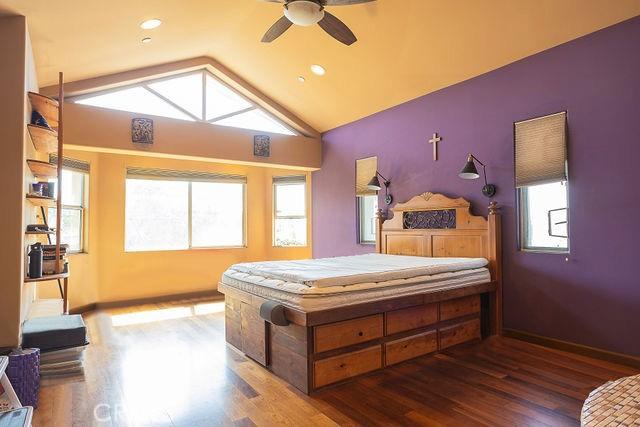 bedroom with wood finished floors, multiple windows, and vaulted ceiling