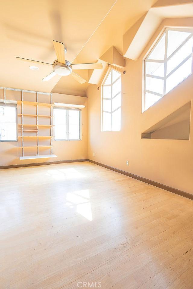 empty room featuring wood finished floors, a ceiling fan, and baseboards