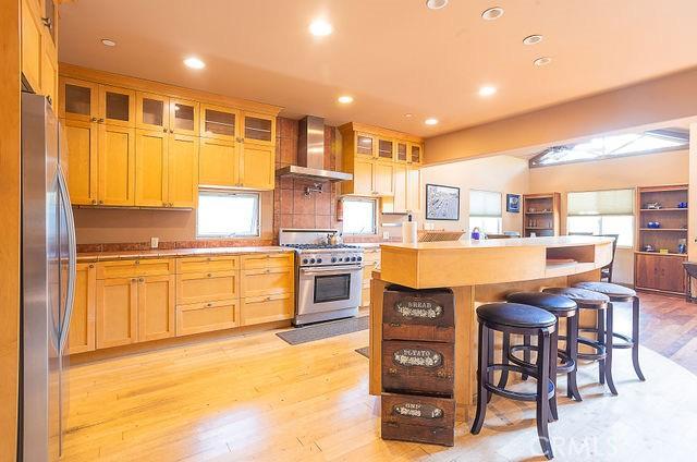 kitchen with a wealth of natural light, a kitchen bar, stainless steel appliances, and wall chimney exhaust hood