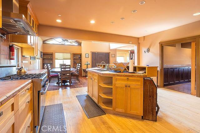 kitchen featuring light wood-type flooring, wall chimney exhaust hood, high end stainless steel range, and recessed lighting