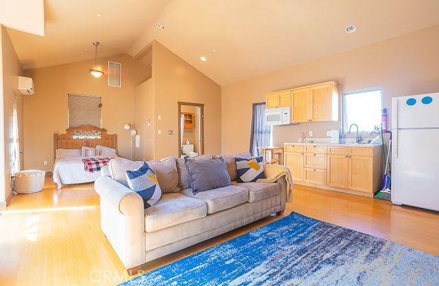 living room featuring visible vents, a wall mounted AC, high vaulted ceiling, and light wood-style floors