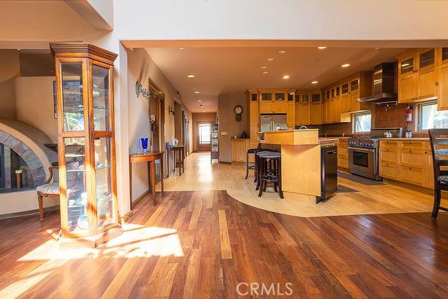 kitchen featuring light hardwood / wood-style flooring, a breakfast bar area, appliances with stainless steel finishes, a kitchen island, and wall chimney exhaust hood