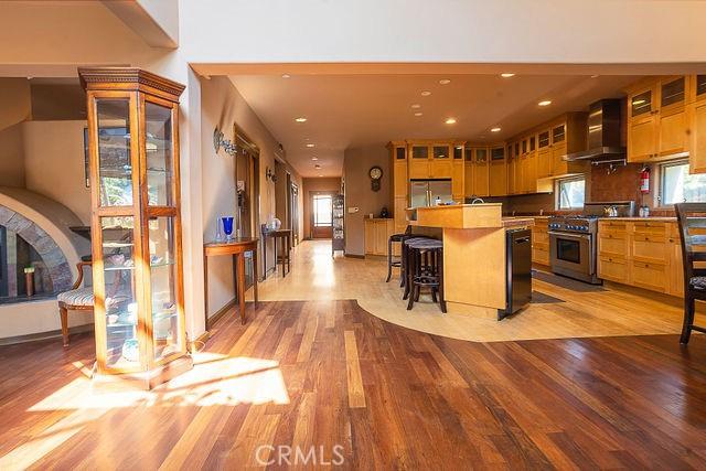 kitchen with recessed lighting, fridge, light wood-style floors, high end stove, and wall chimney exhaust hood