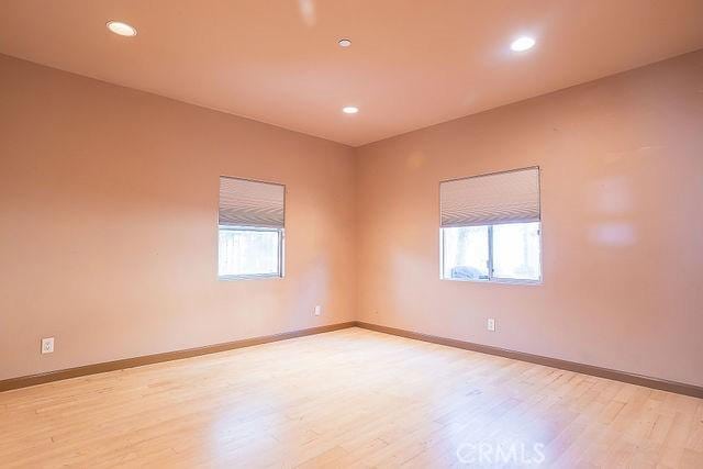 spare room featuring baseboards, a wealth of natural light, and light wood-type flooring