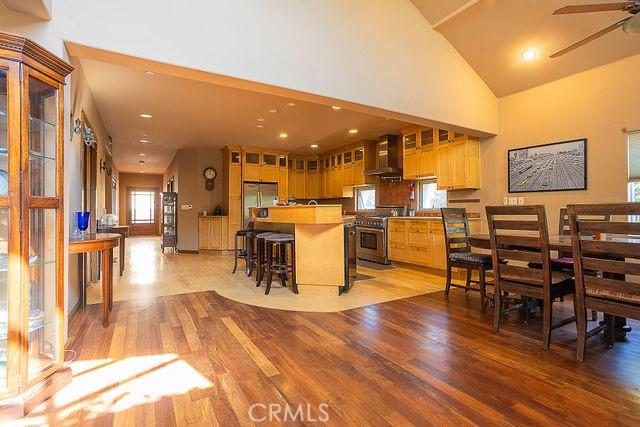 kitchen featuring glass insert cabinets, light wood-style floors, appliances with stainless steel finishes, a ceiling fan, and wall chimney exhaust hood