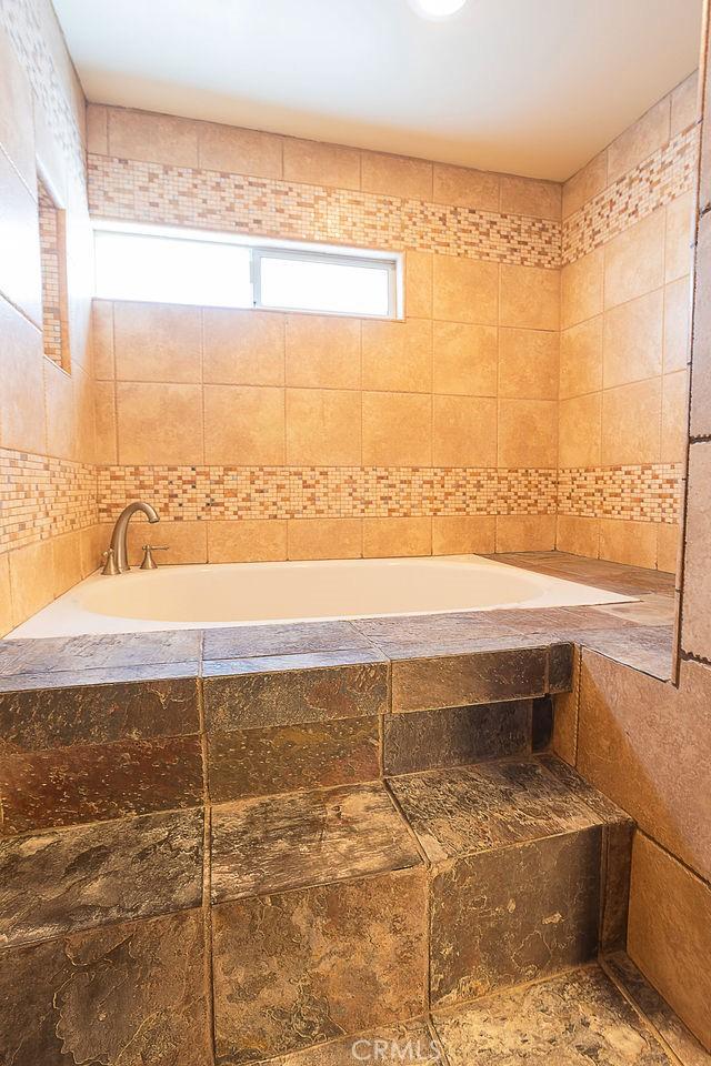 bathroom with a garden tub and tile walls