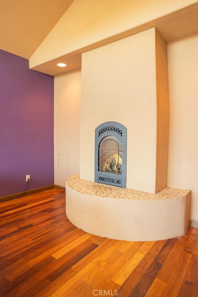 interior space featuring baseboards, wood finished floors, lofted ceiling, and a fireplace with raised hearth