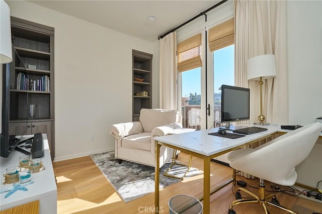 home office with built in features and light wood-type flooring