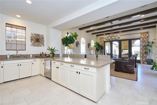 kitchen featuring pendant lighting, beamed ceiling, sink, white cabinets, and kitchen peninsula