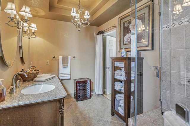 bathroom featuring a shower with shower door, a chandelier, vanity, a tray ceiling, and tile patterned flooring