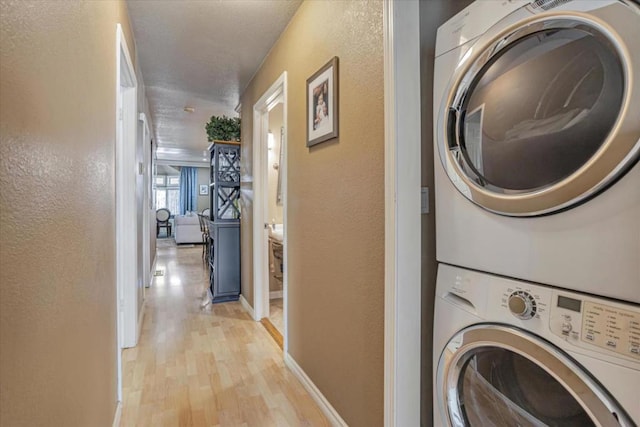 laundry room with stacked washer / dryer and light wood-type flooring