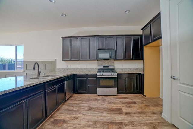 kitchen with sink, dark brown cabinetry, light wood-type flooring, stainless steel appliances, and light stone counters