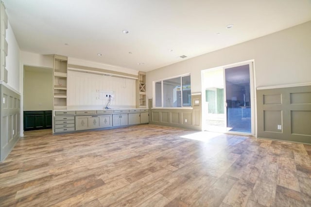 unfurnished living room featuring sink and light hardwood / wood-style floors