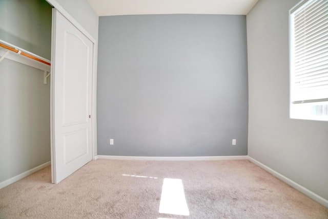 unfurnished bedroom featuring light carpet and a closet