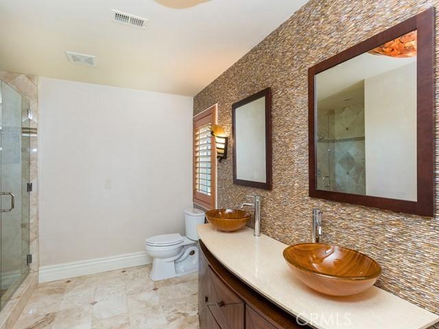 bathroom with decorative backsplash, toilet, vanity, and walk in shower