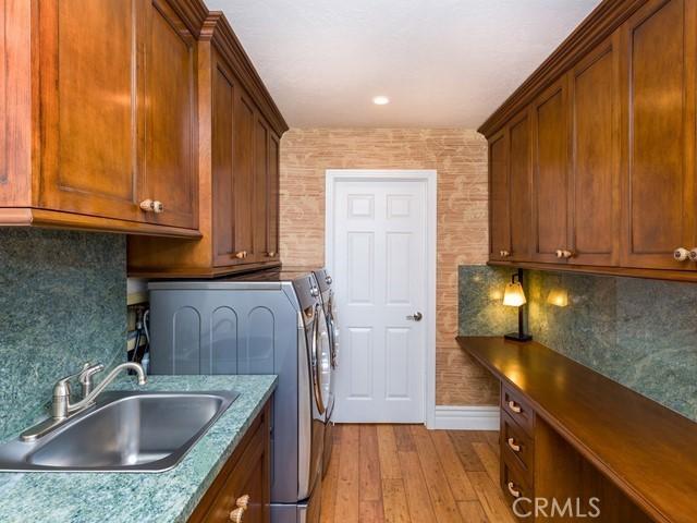 washroom featuring cabinets, washing machine and clothes dryer, sink, and light hardwood / wood-style flooring