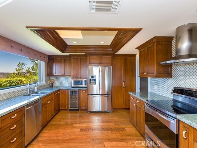44665 La Cruz Dr, Temecula, CA 92590 - kitchen featuring appliances with stainless steel finishes, wine cooler, wall chimney range hood, decorative backsplash, and ornamental molding
