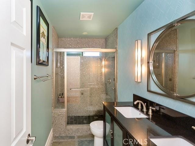 bathroom featuring tile patterned flooring, vanity, toilet, and a shower with door