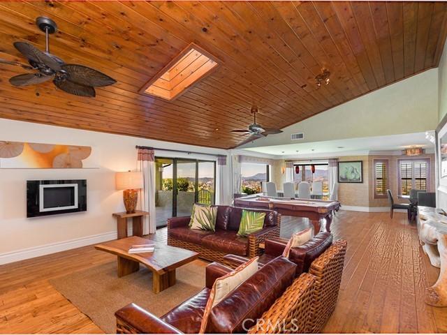 living room featuring a skylight, plenty of natural light, wooden ceiling, and light hardwood / wood-style flooring