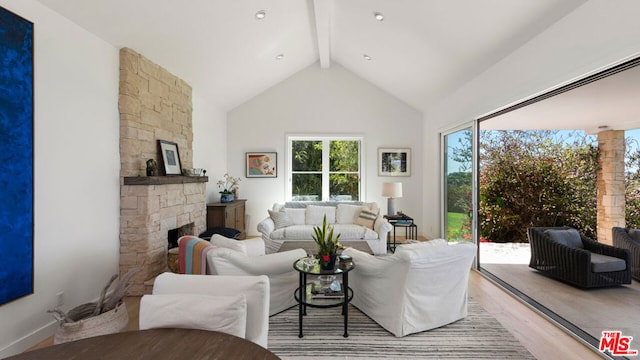 living room with beam ceiling, high vaulted ceiling, light hardwood / wood-style floors, and a stone fireplace