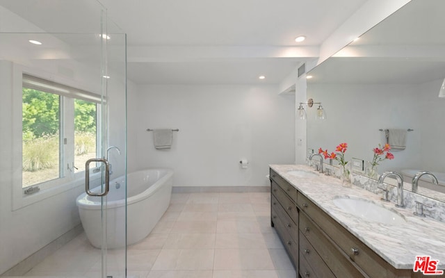 bathroom with tile patterned flooring, vanity, a tub, and a wealth of natural light