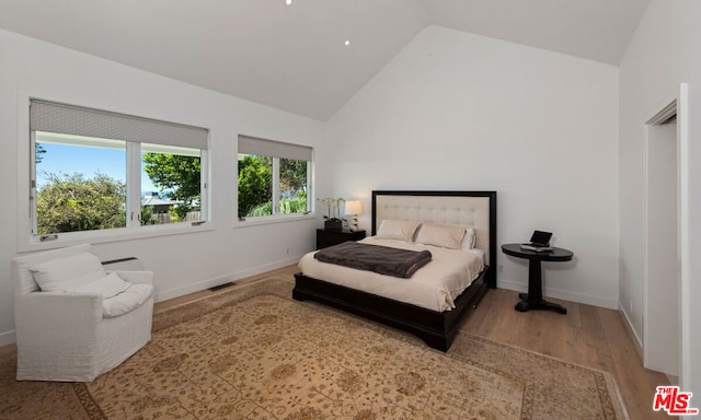 bedroom with light hardwood / wood-style floors and lofted ceiling