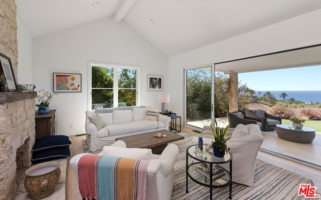 living room with beamed ceiling, a water view, a healthy amount of sunlight, and light hardwood / wood-style floors