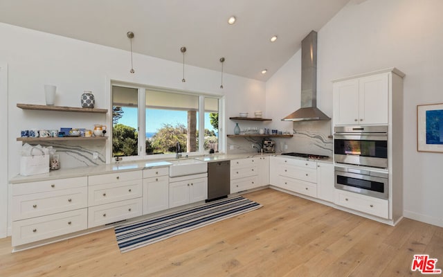 kitchen featuring white cabinets, wall chimney exhaust hood, stainless steel appliances, and light hardwood / wood-style floors