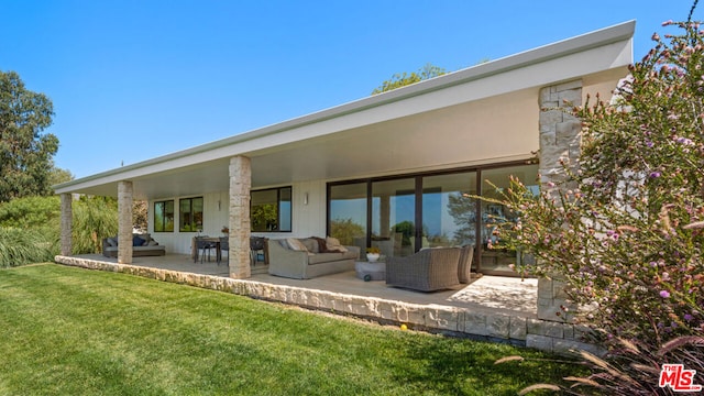 rear view of house with a yard, a patio, and an outdoor hangout area