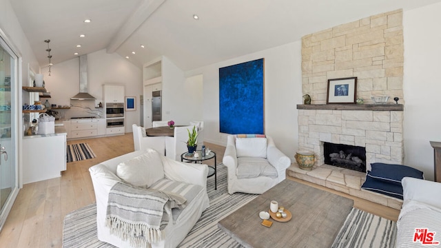 living room featuring vaulted ceiling with beams, a stone fireplace, and light hardwood / wood-style floors