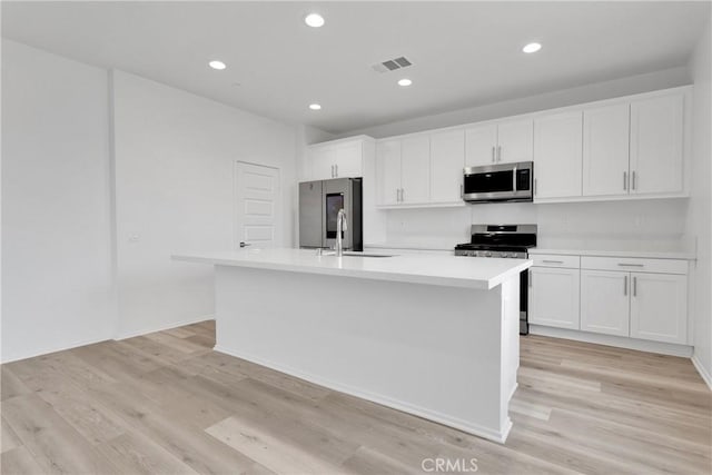 kitchen featuring sink, white cabinetry, a center island with sink, and stainless steel appliances