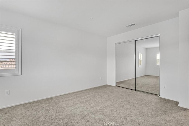 unfurnished bedroom featuring light colored carpet and a closet