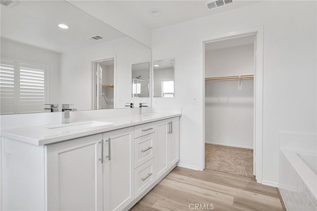 bathroom featuring tiled bath, vanity, and hardwood / wood-style flooring