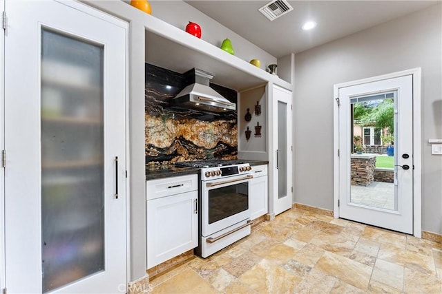 kitchen featuring decorative backsplash, white cabinetry, white range with gas stovetop, and wall chimney range hood