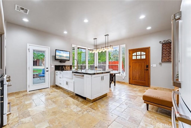 kitchen featuring dark stone counters, white cabinets, decorative light fixtures, dishwashing machine, and white range oven