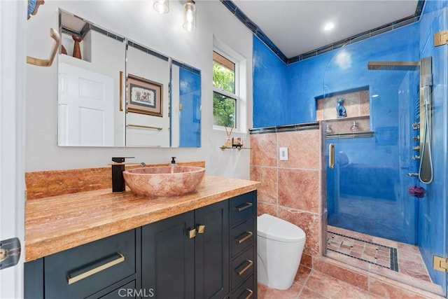 bathroom with an enclosed shower, vanity, toilet, and tile walls