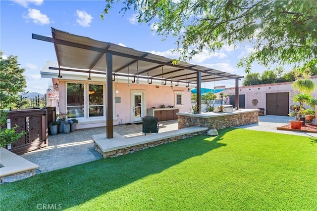 back of house featuring a pergola, a patio area, a yard, and exterior kitchen