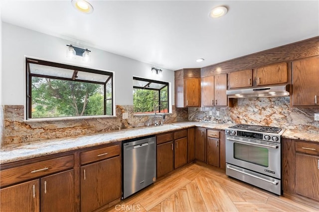 kitchen with backsplash, sink, appliances with stainless steel finishes, and light parquet flooring