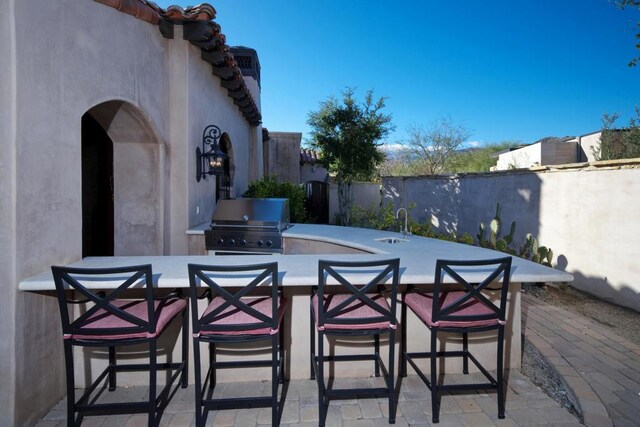 view of patio with area for grilling, exterior kitchen, and a wet bar