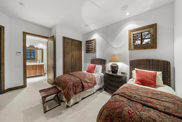 bedroom featuring connected bathroom and light carpet