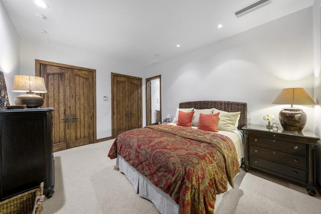 bedroom featuring light carpet and two closets