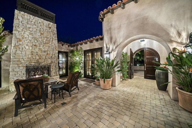 patio at night featuring an outdoor stone fireplace