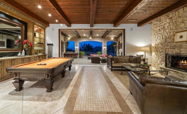 rec room with beamed ceiling, a stone fireplace, pool table, and wood ceiling