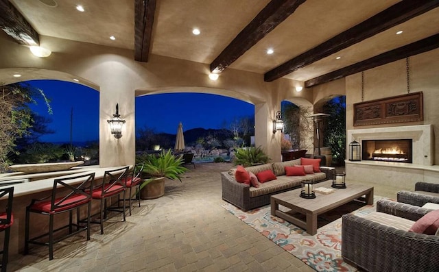 patio at night featuring an outdoor living space with a fireplace and a bar